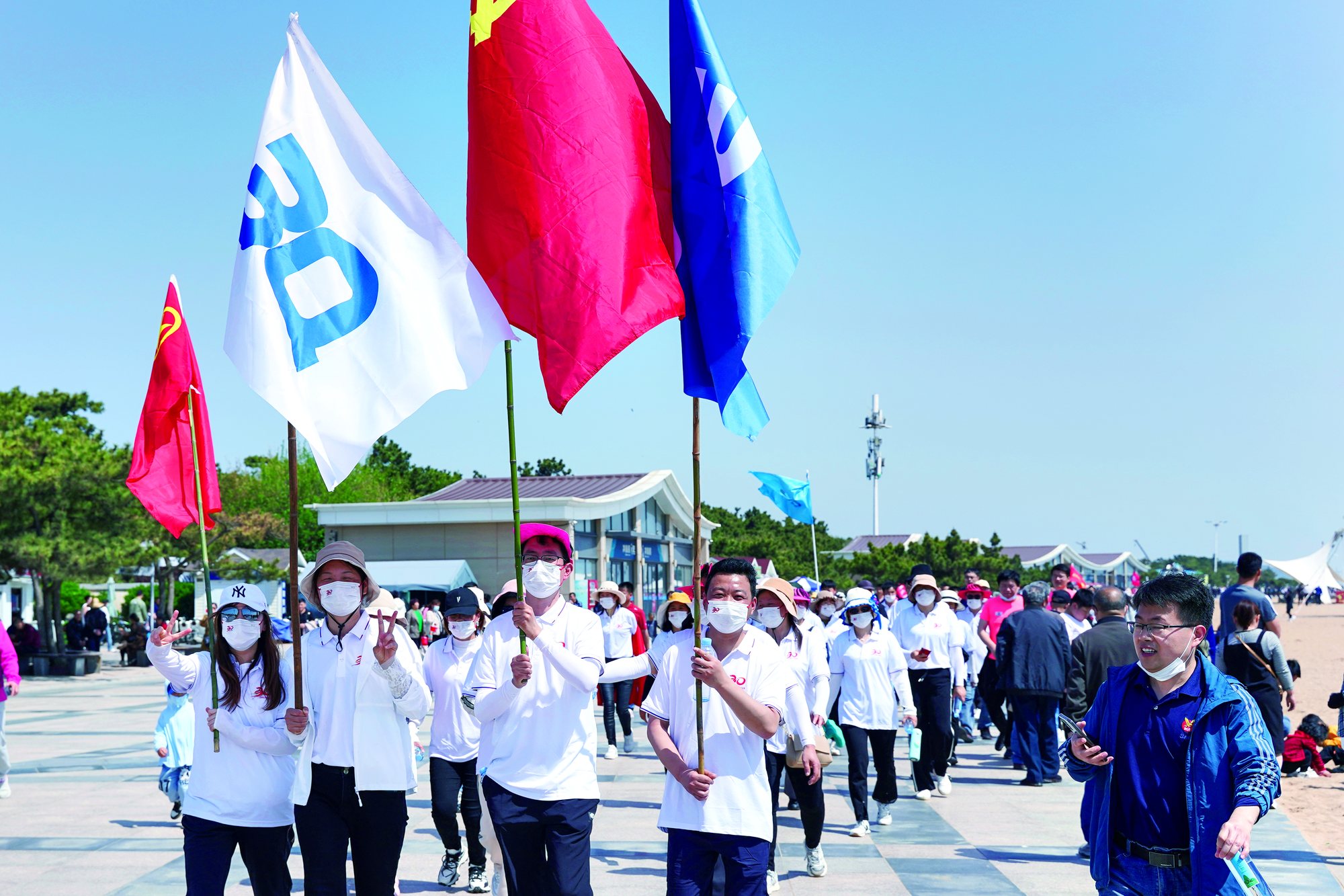 Sanqi employees walking together while carrying company flags